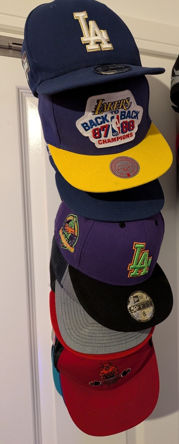 Baseball cap collection hanging on a door