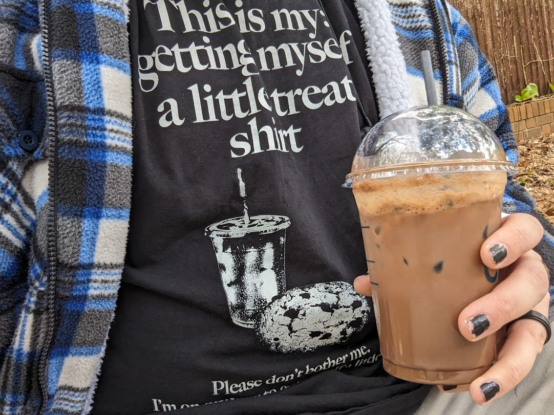 My &ldquo;getting myself a little treat&rdquo; shirt, holding an iced coffee
